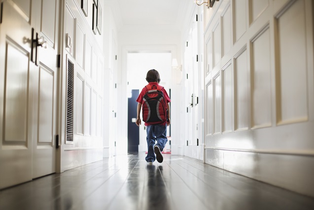 boy walking in hallway wearing backpack