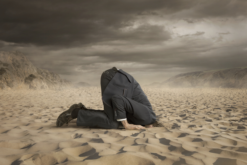 man in suit with head in the sand