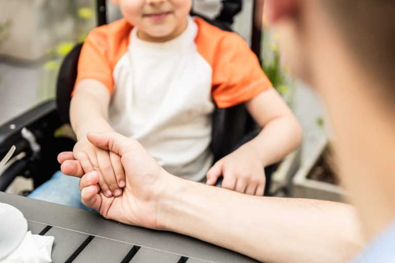 holding hand of boy in a wheelchair