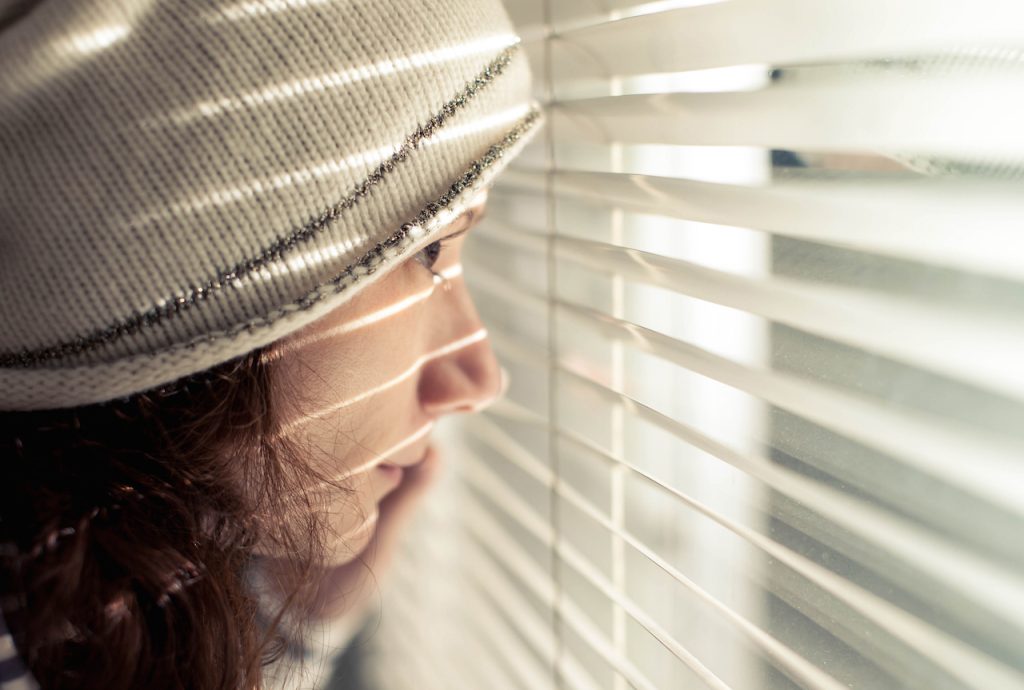 Girl looking through blinds