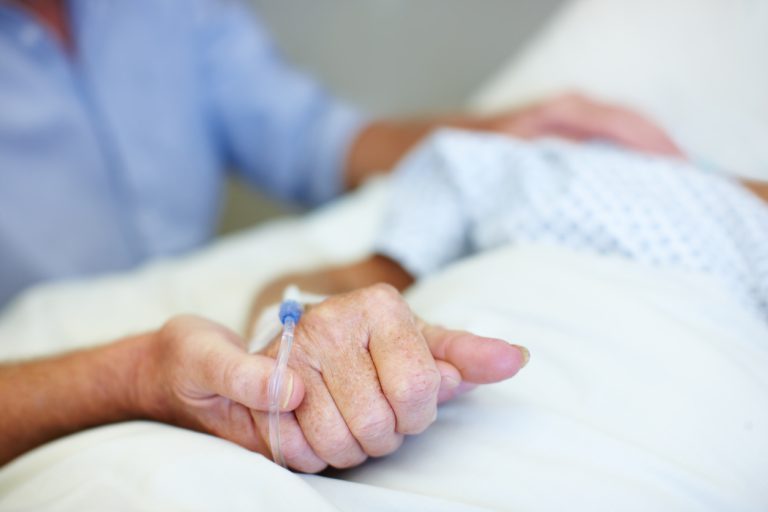 holding hand of woman in hospital bed