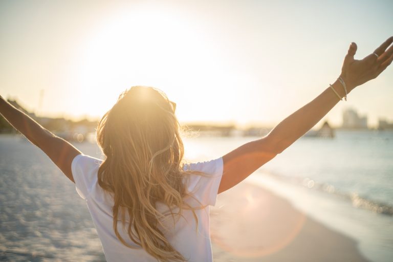 woman on beech embracing sunlight